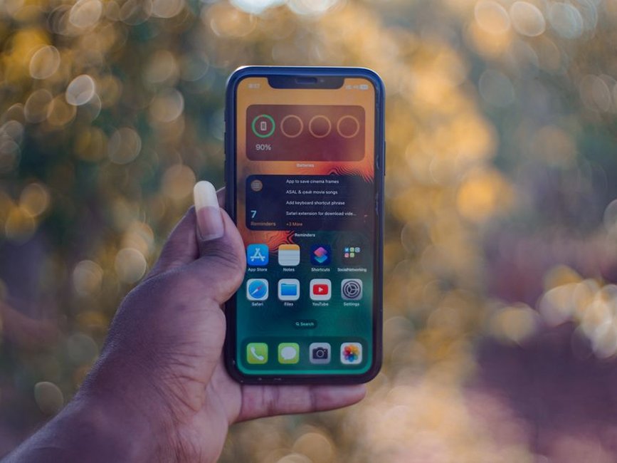 Une main tient un smartphone affichant son écran d’accueil