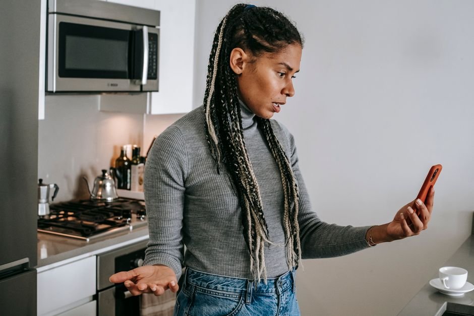 Une femme agacée fixe son smartphone dans une cuisine