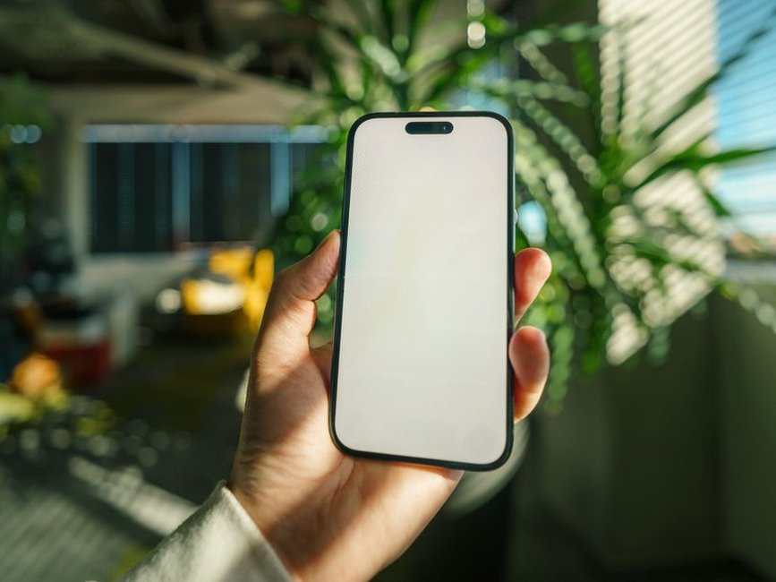 Hand holding a new iPhone showing the Settings screen