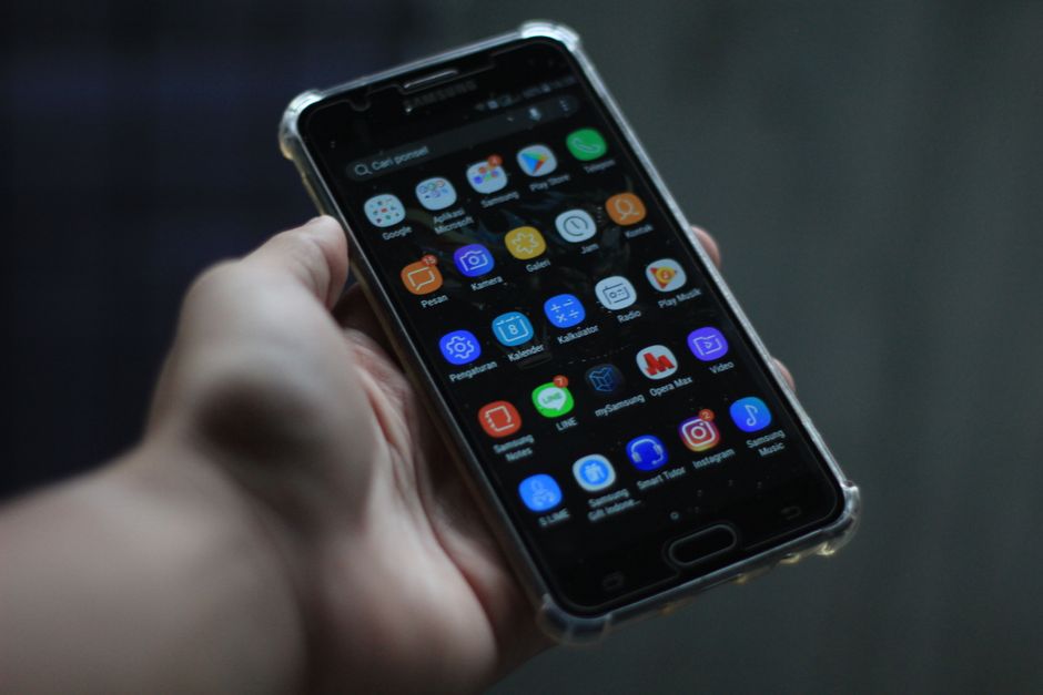 Une main tenant un smartphone Android ouvert sur l'écran des paramètres