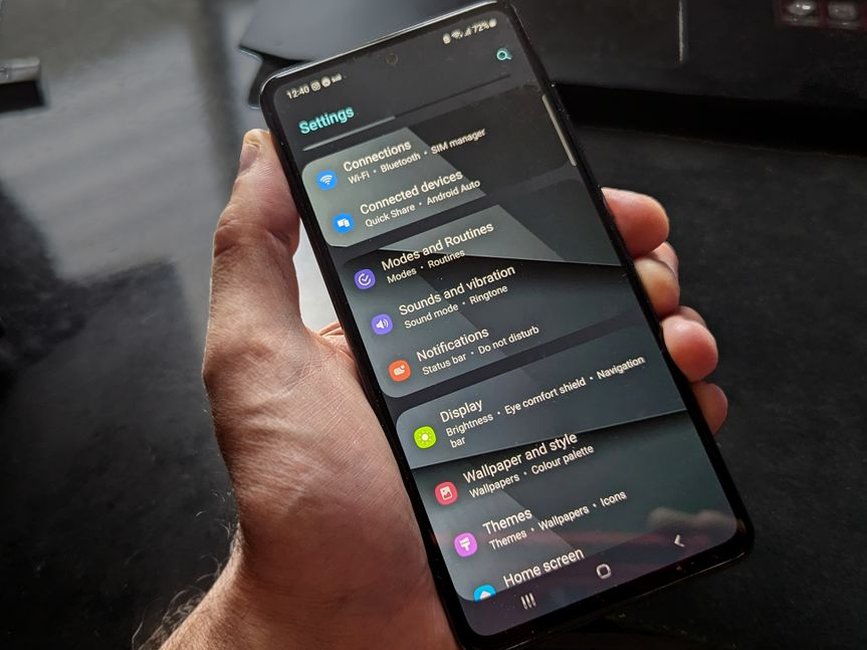Hand holding an Android smartphone open on its settings screen