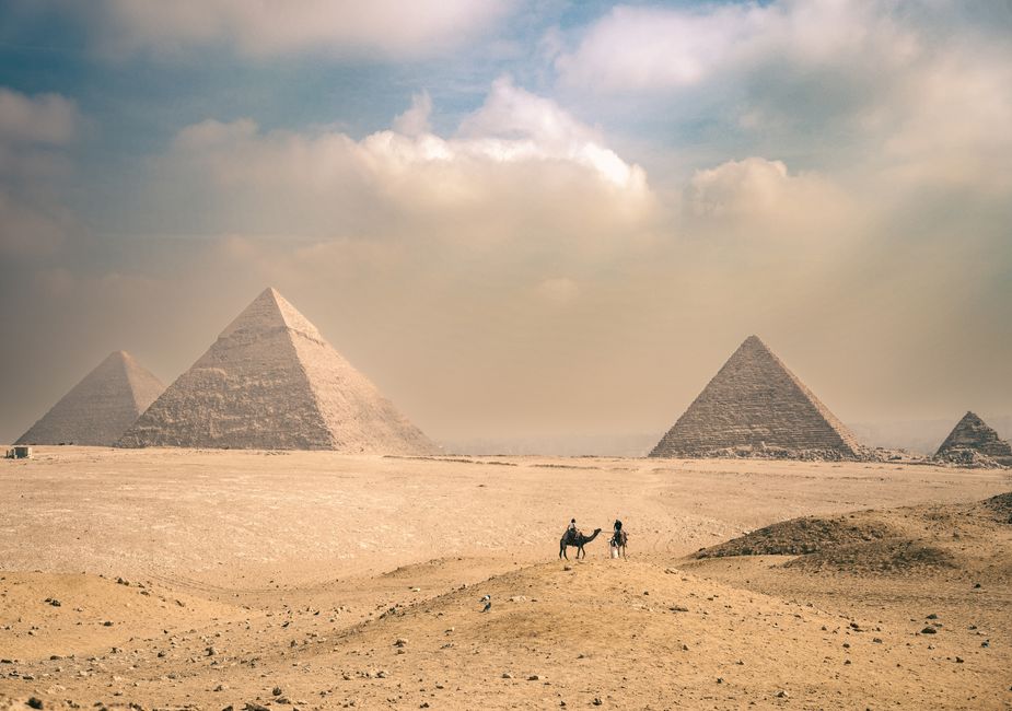 The Giza pyramids with two camel riders crossing the desert in front
