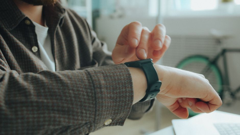 Eine Person mit Smartwatch am Handgelenk und Smartphone in der Hand